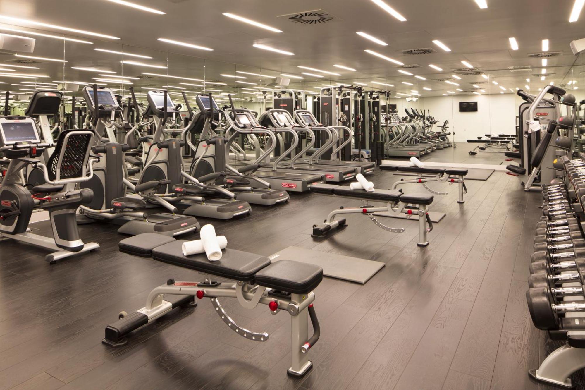 Готель Sea Containers Лондон Екстер'єр фото The photo shows a modern gym interior. There are several exercise machines arranged neatly, including treadmills and weight training machines. The floor is dark, and the gym is well-lit with overhead lighting. In the foreground, there are benches for